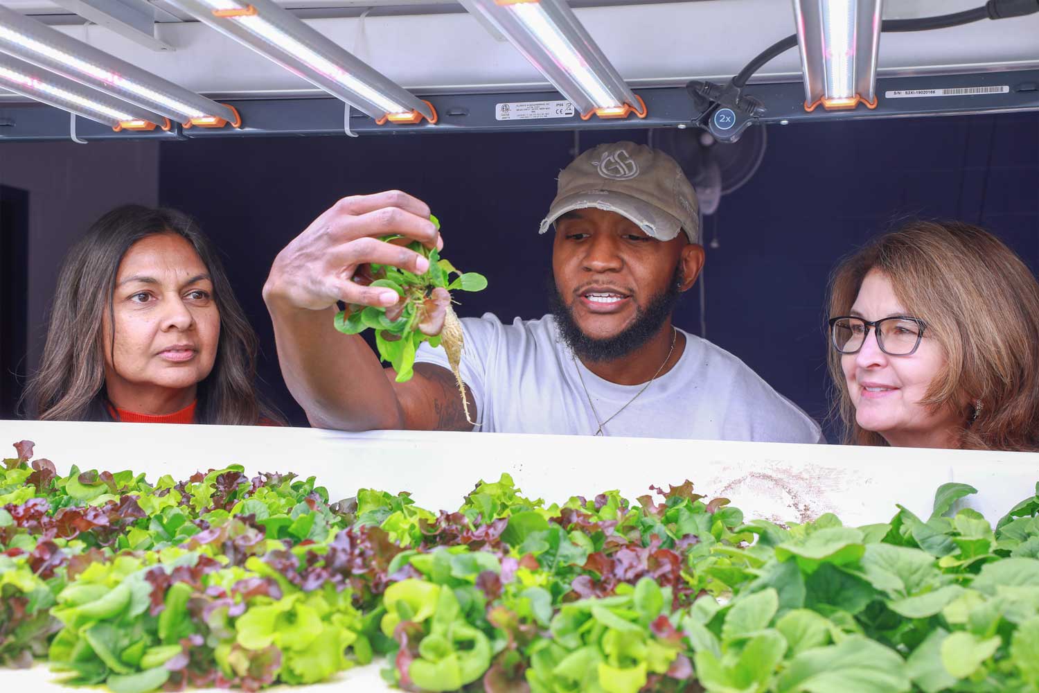 Desmond Hayes showing plant roots to visitors at iA Labs at The College of New Jersey